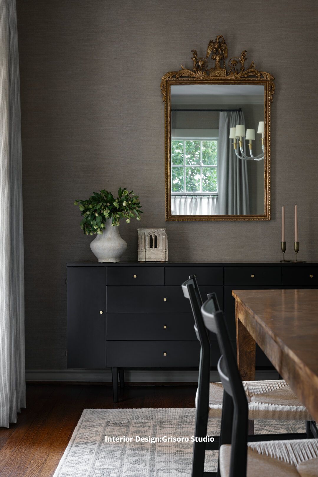 A dining room with a black dresser and a mirror above it
