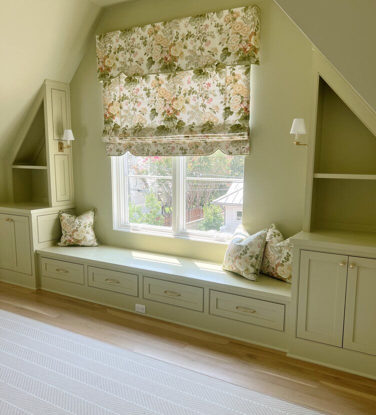 A bedroom with built in window seat and floral curtains