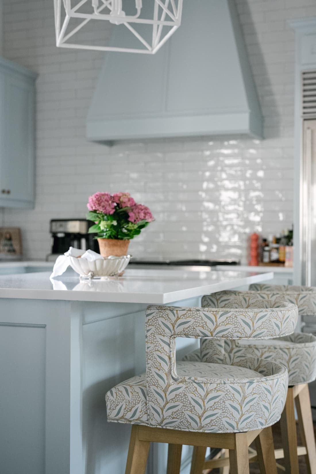 A redesigned kitchen with stools and a potted plant on the counter.
