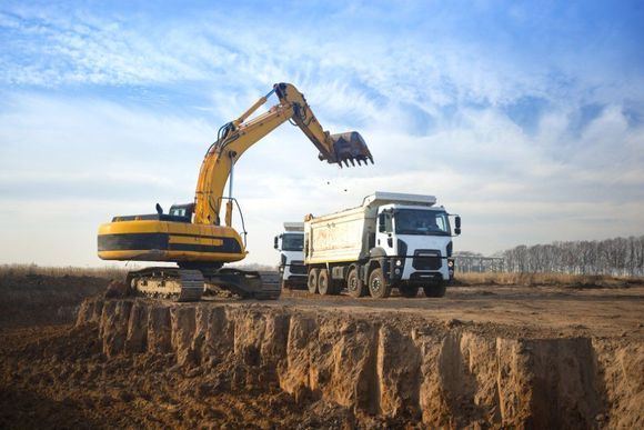 excavator loads soil on a truck