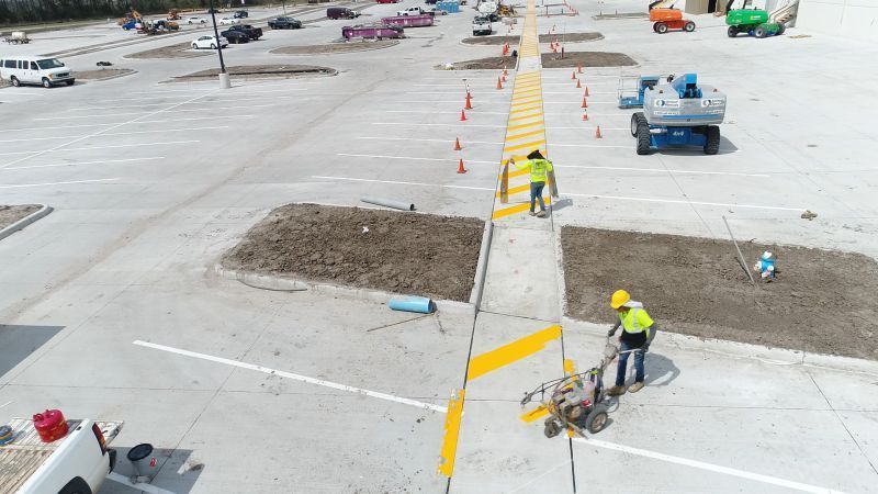 A group of construction workers are working on a parking lot.