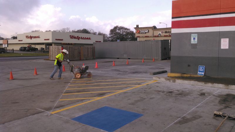 A man is painting a handicapped parking space in a parking lot.