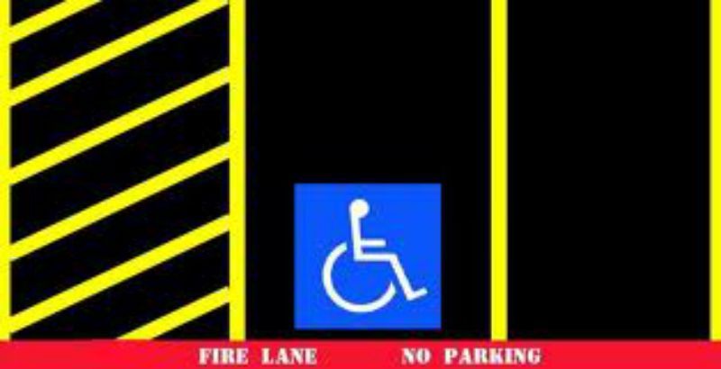 A handicapped sign is in the middle of a parking lot