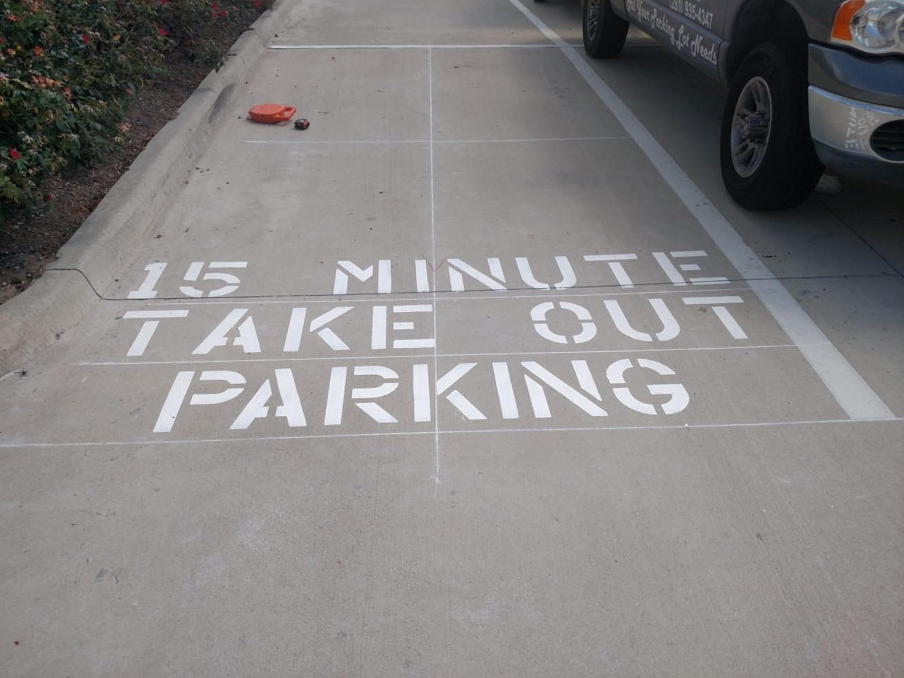 A 15 minute take out parking sign is painted on the sidewalk