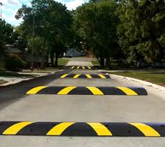 A black and yellow speed bump on the side of a road.