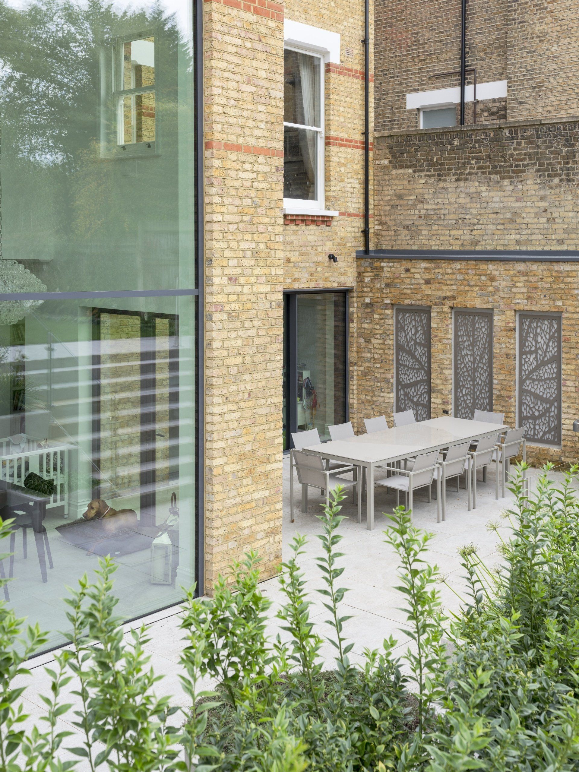 A patio with a table and chairs in front of a brick building.