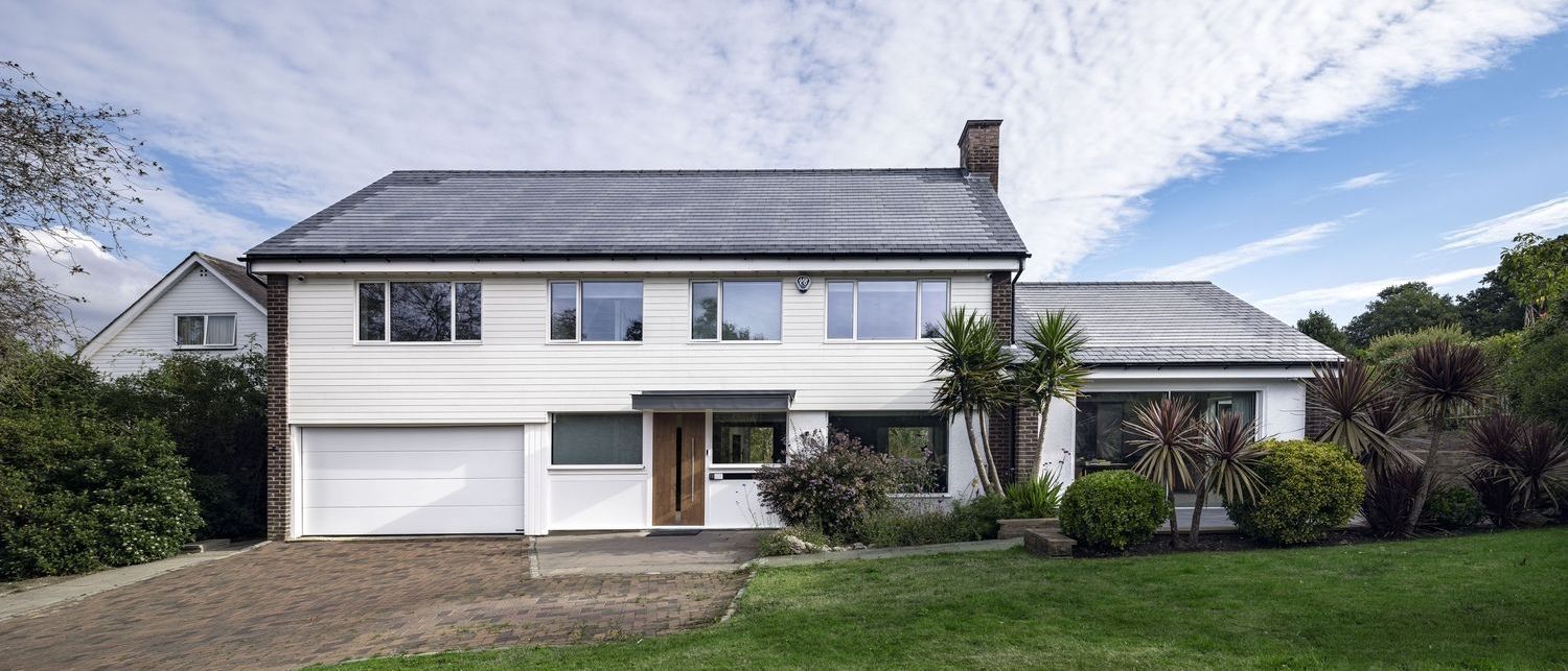 A small white house with a chimney and a british homes awards logo in the background.