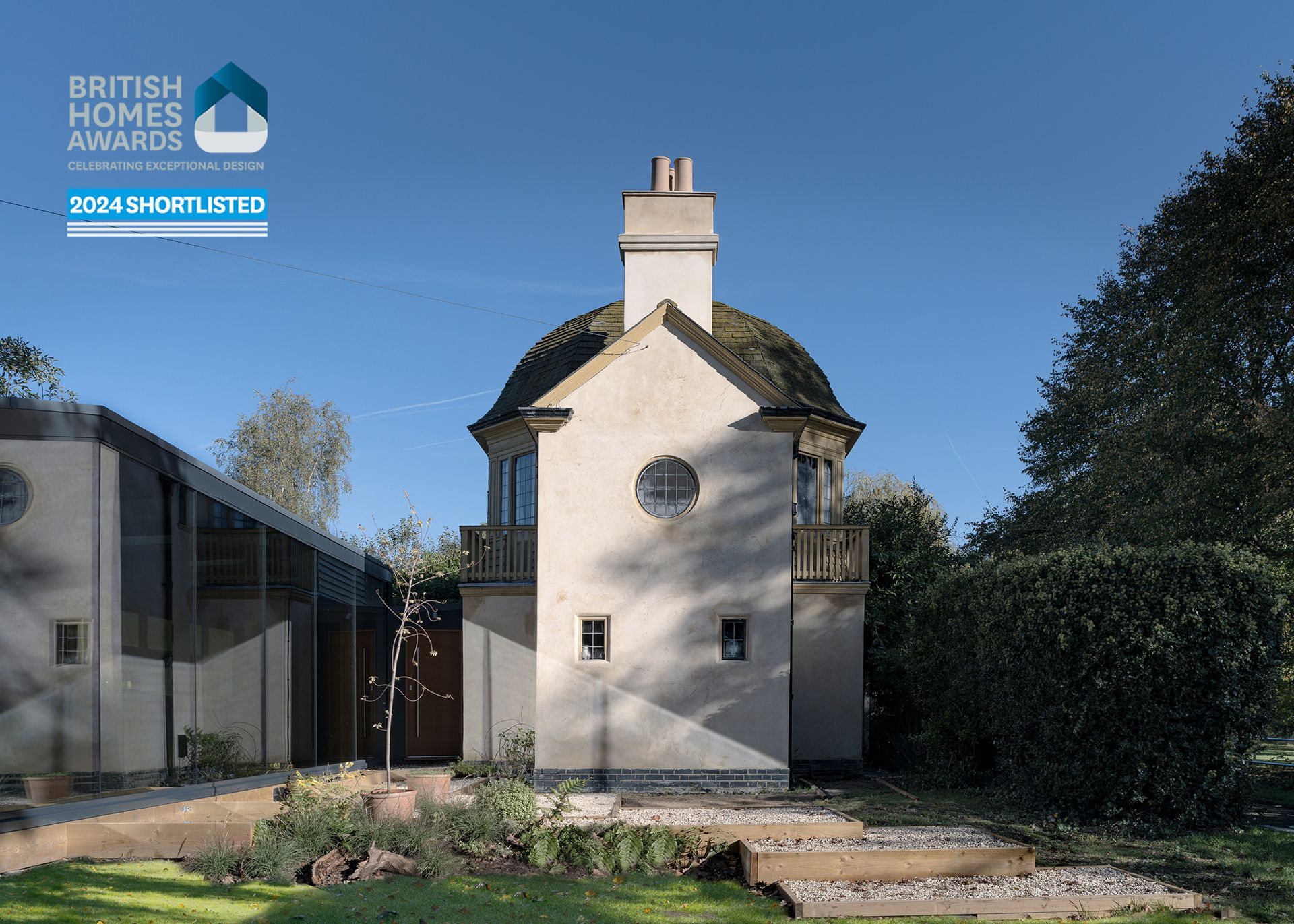 A small white house with a chimney and a british homes awards logo in the background.