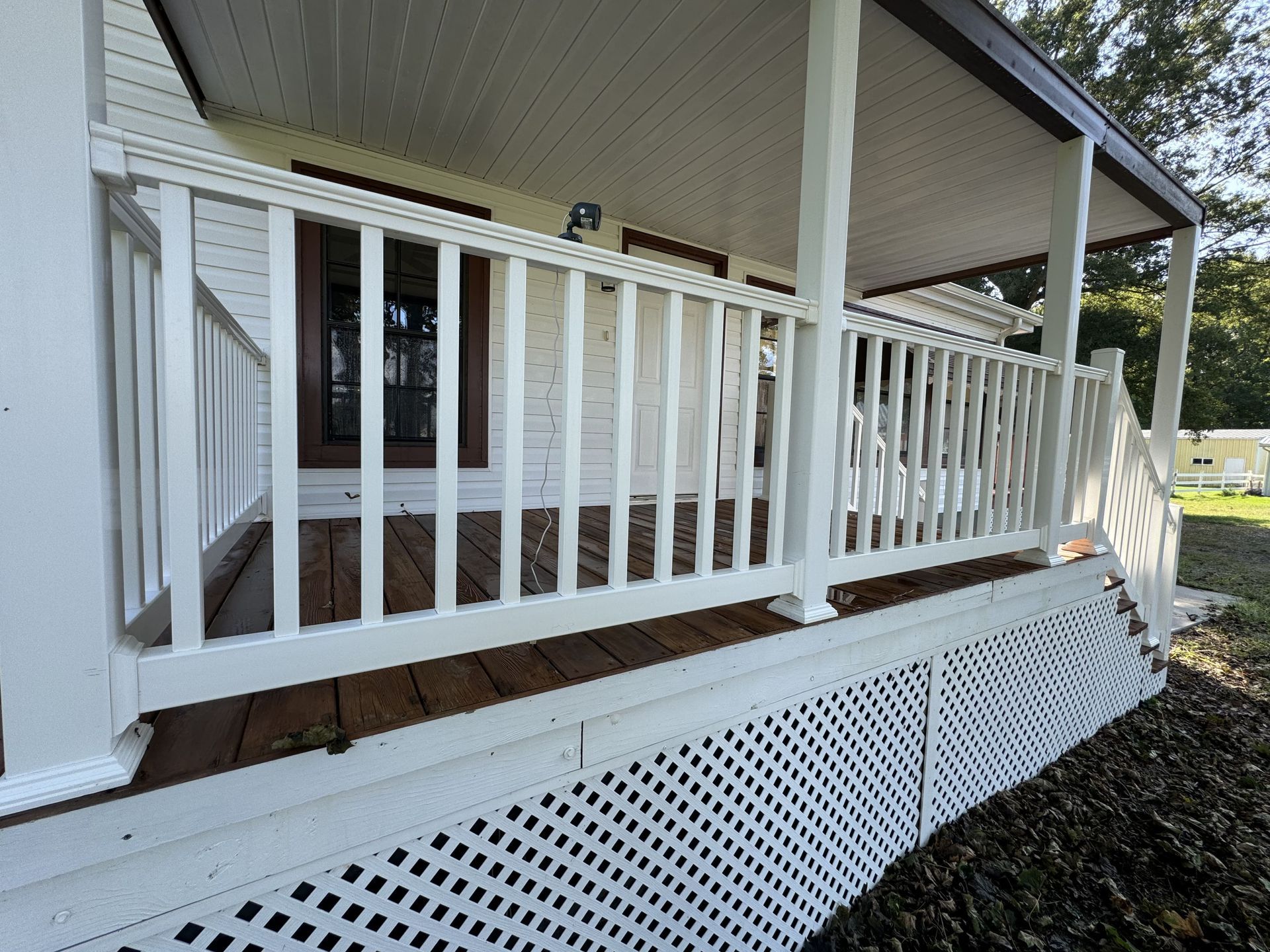 White porch with railing and lattice.