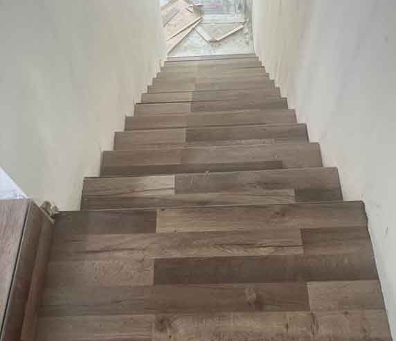 Wooden tile steps lead upward between white walls.