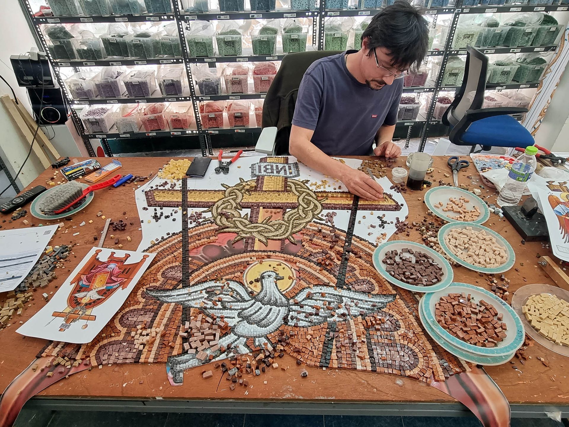 Byzantine mosaic artisan assembling cross and dove throne mosaic with tesserae and tools in Greek iconography studio