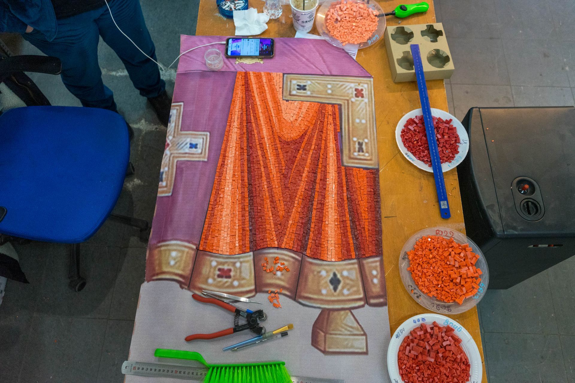 Mosaic Altar Table in progress with orange drapery, tesserae, tile nippers, tweezers, and tools in Byzantine icon studio