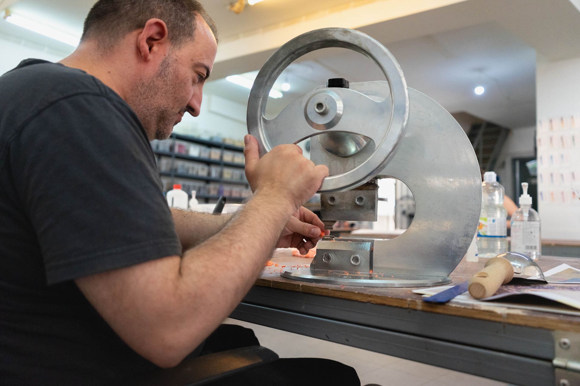 Artisan cutting mosaic smalti tesserae on heavy tile-cutting machine in Byzantine Artworks' Athens studio.