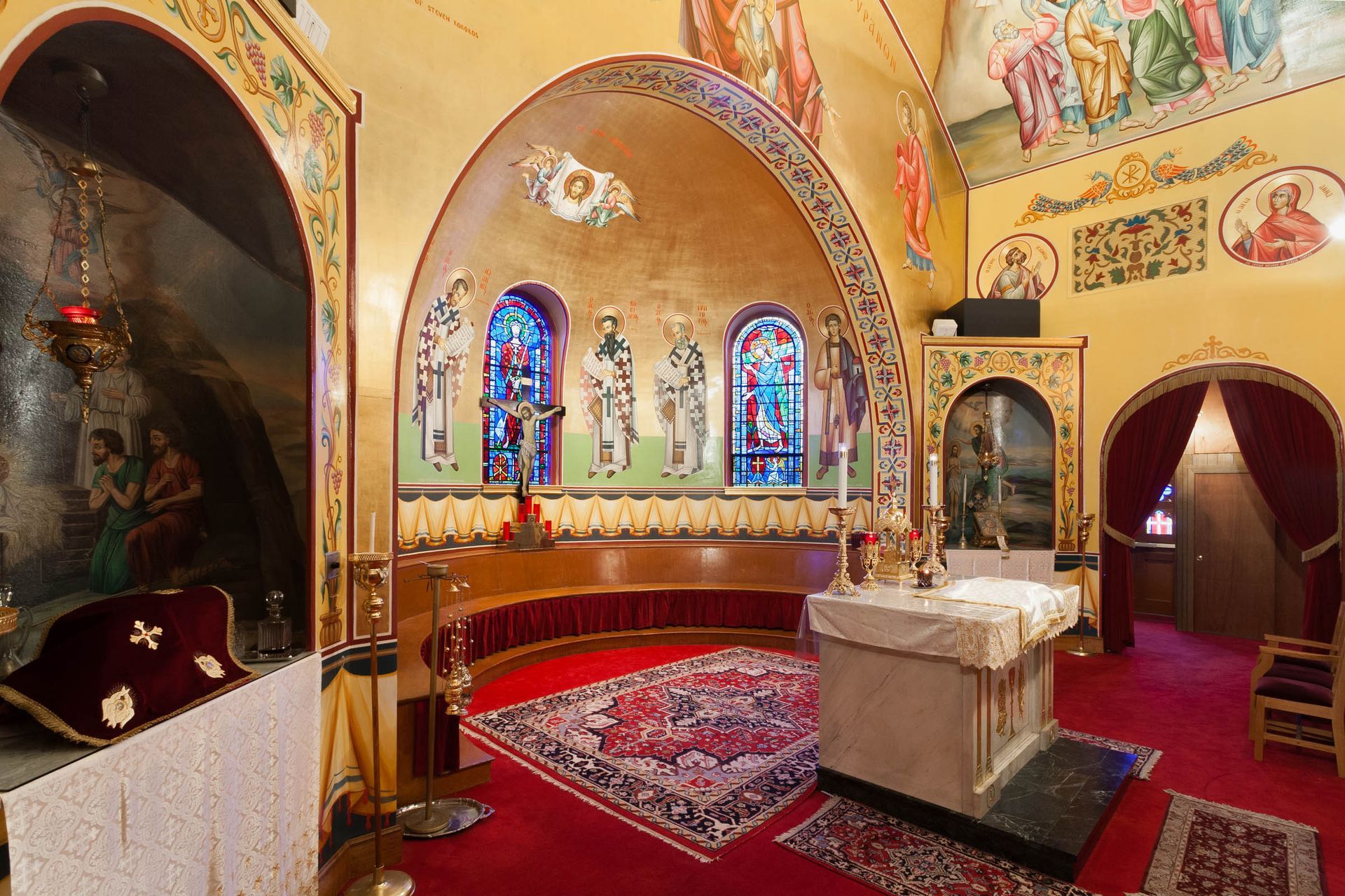 Orthodox altar iconography with gold-leaf walls, hierarch saints and stained-glass windows at Taxiarchae Church Watertown, MA