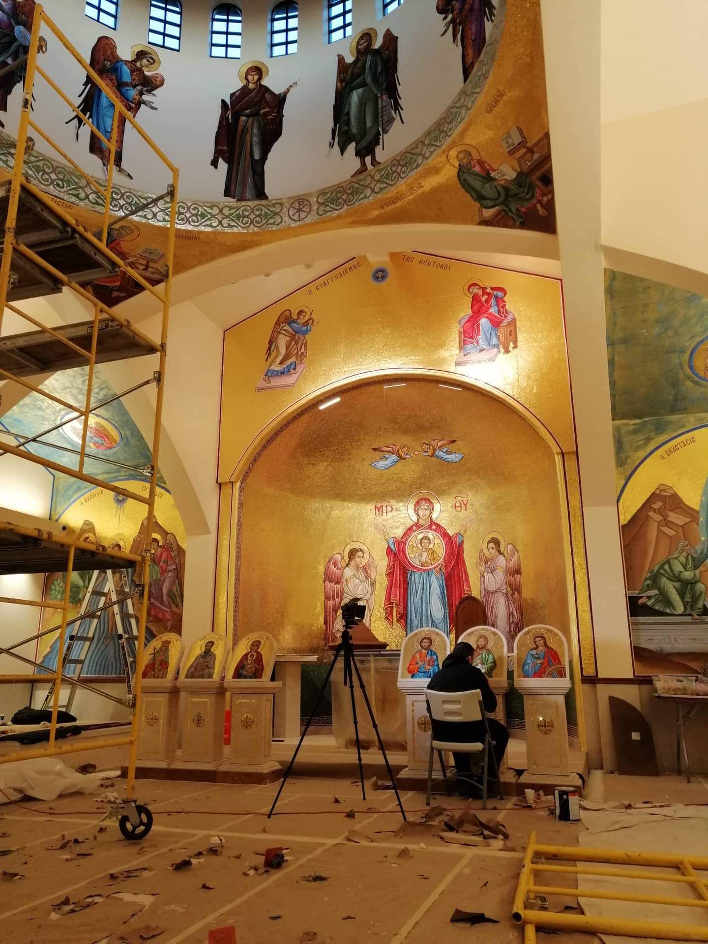 Artisan installing Byzantine church mosaics in Denver chapel with scaffolding, icon screen work, & barrell dome preparations.