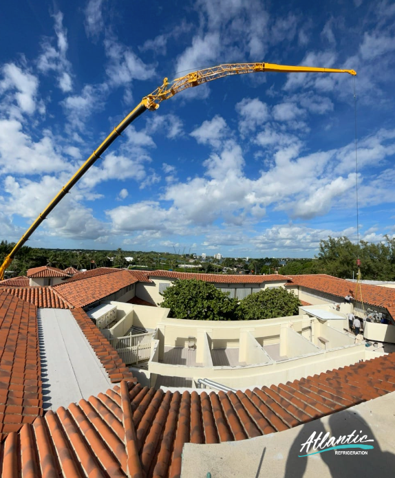 A yellow crane over a building with a red-tiled roof and a central courtyard under a blue sky.