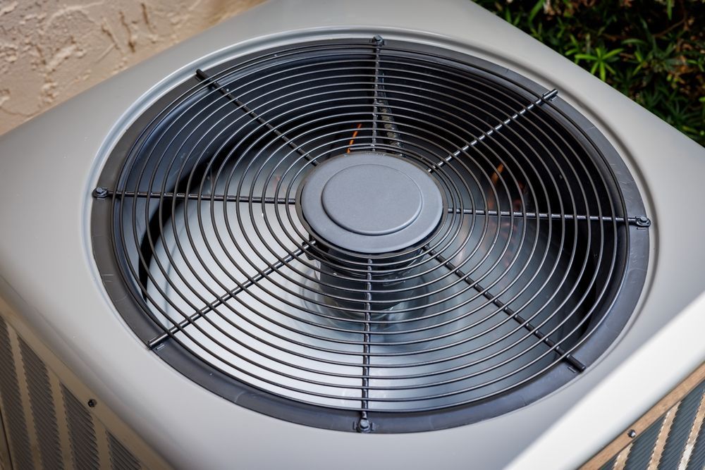 Air conditioning unit with a fan and protective metal grille.