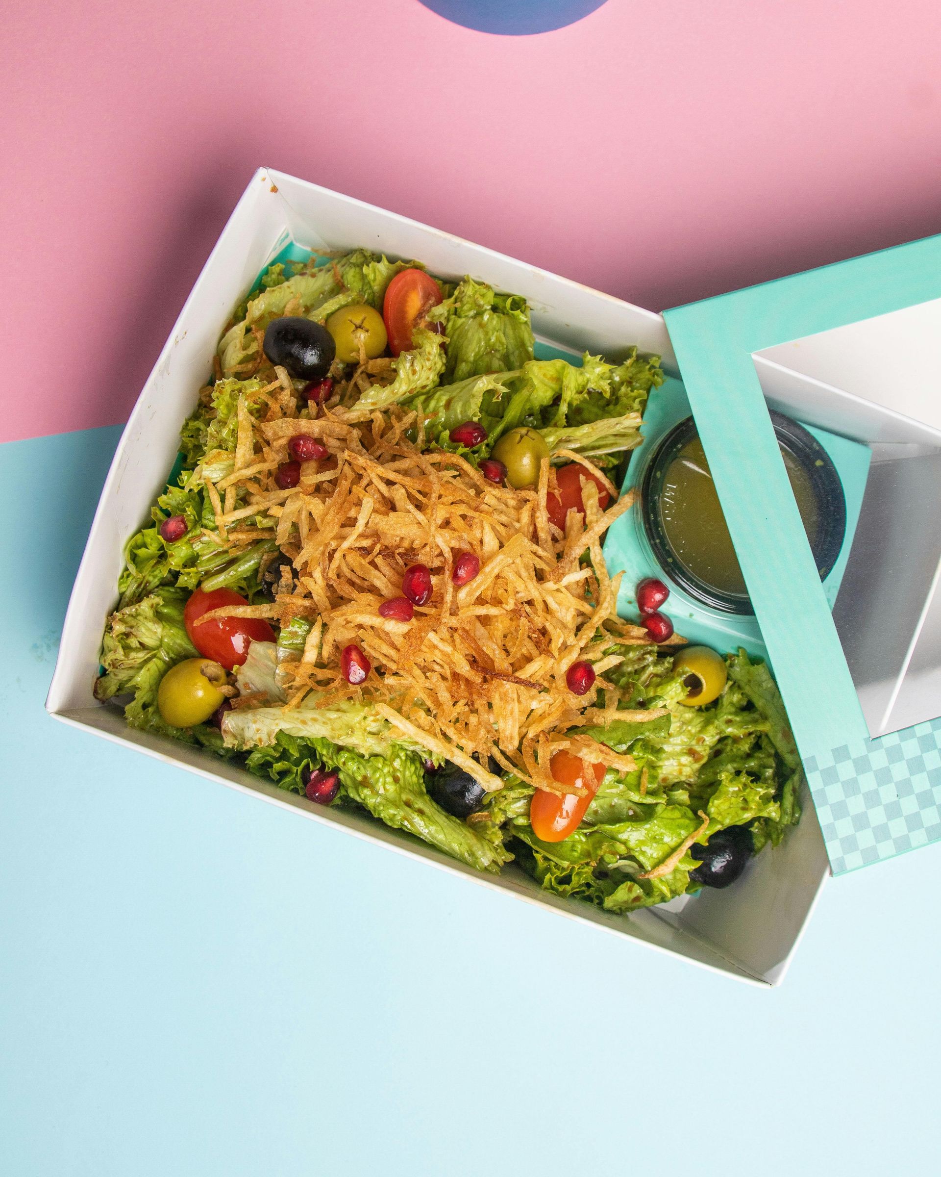 A salad in a box with the lid open on a table.