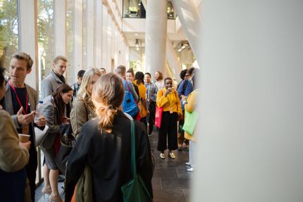 A group of people are standing in a hallway talking to each other.