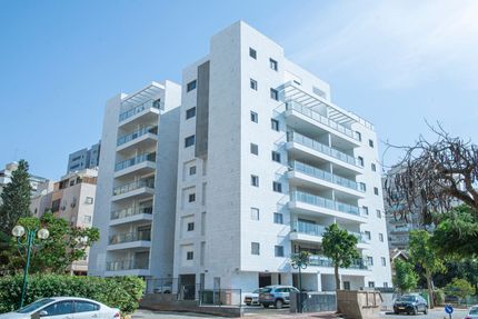 A large white building with cars parked in front of it.