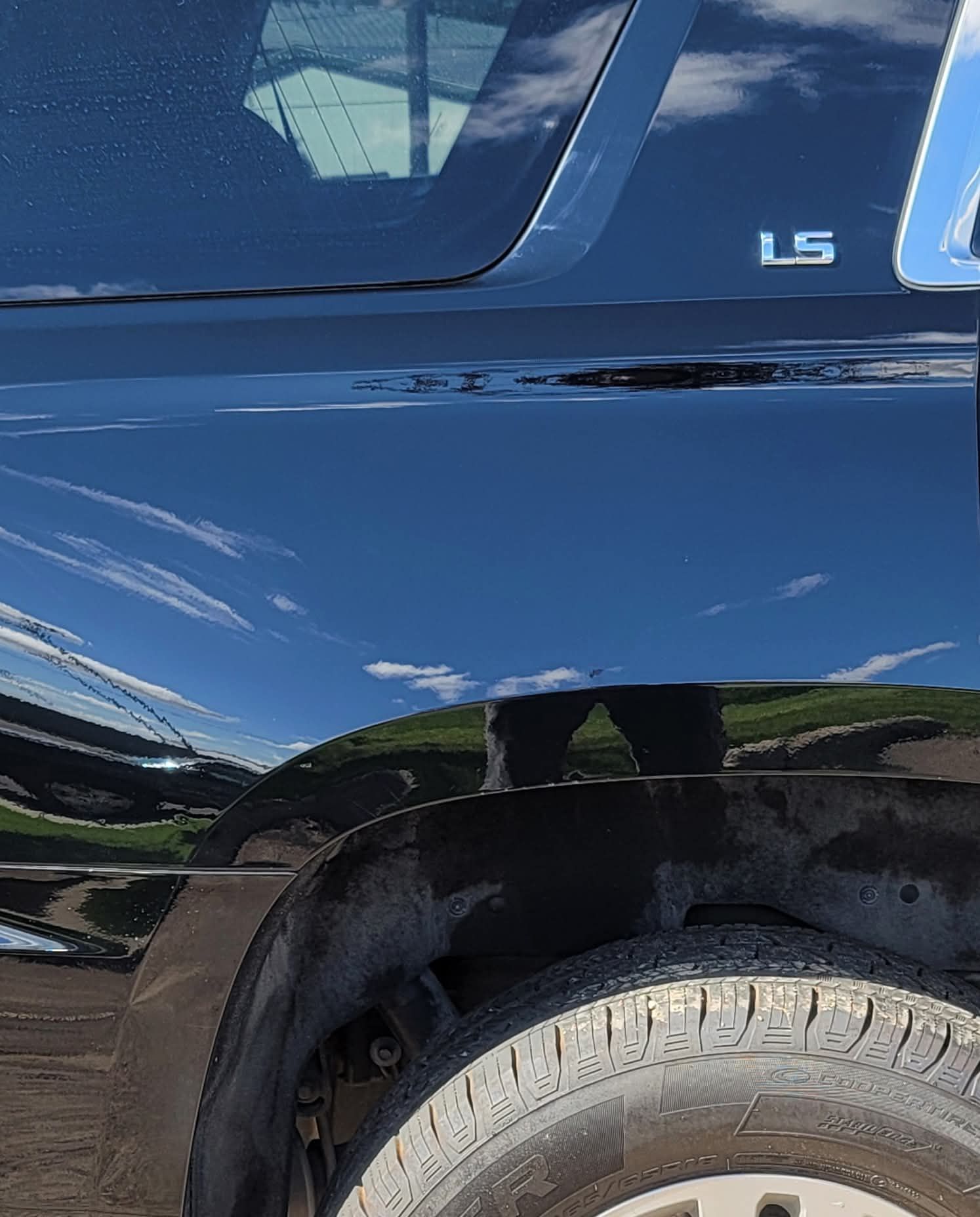 A dark blue car’s rear fender and tire, featuring an LS trim badge on the side panel.
