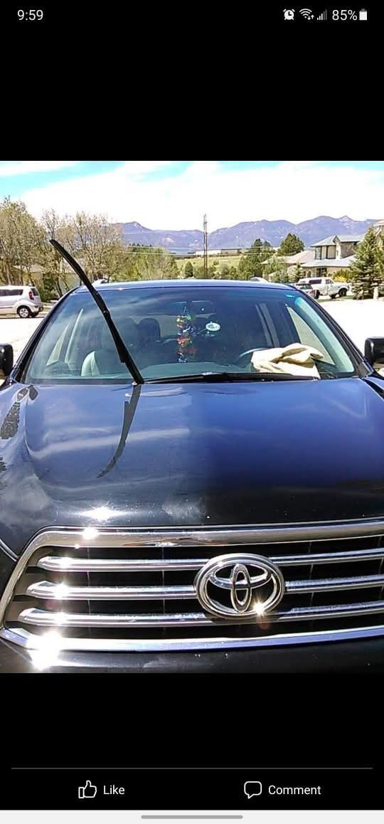 A dark-colored Toyota SUV parked outdoors with a single windshield wiper pointing straight up into the air.