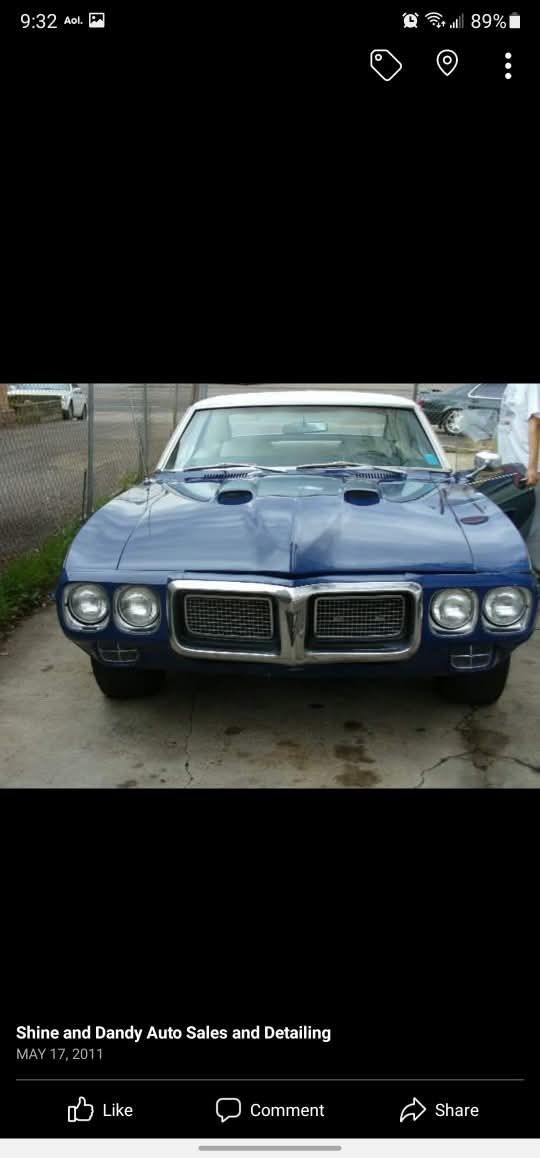 A blue Pontiac Firebird parked on a concrete surface, viewed from the front.