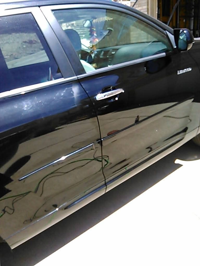 A close-up, angled view of the side of a black sedan, showing the front and rear doors and the side mirror.