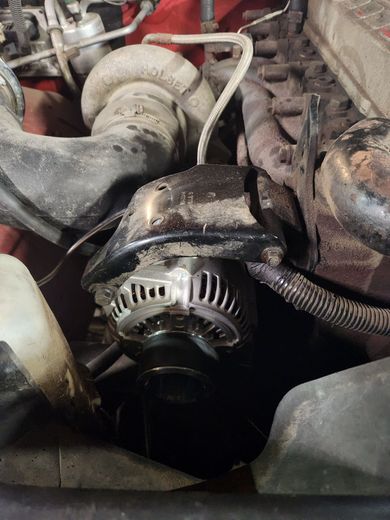 A close up of a car engine with a hose attached to it