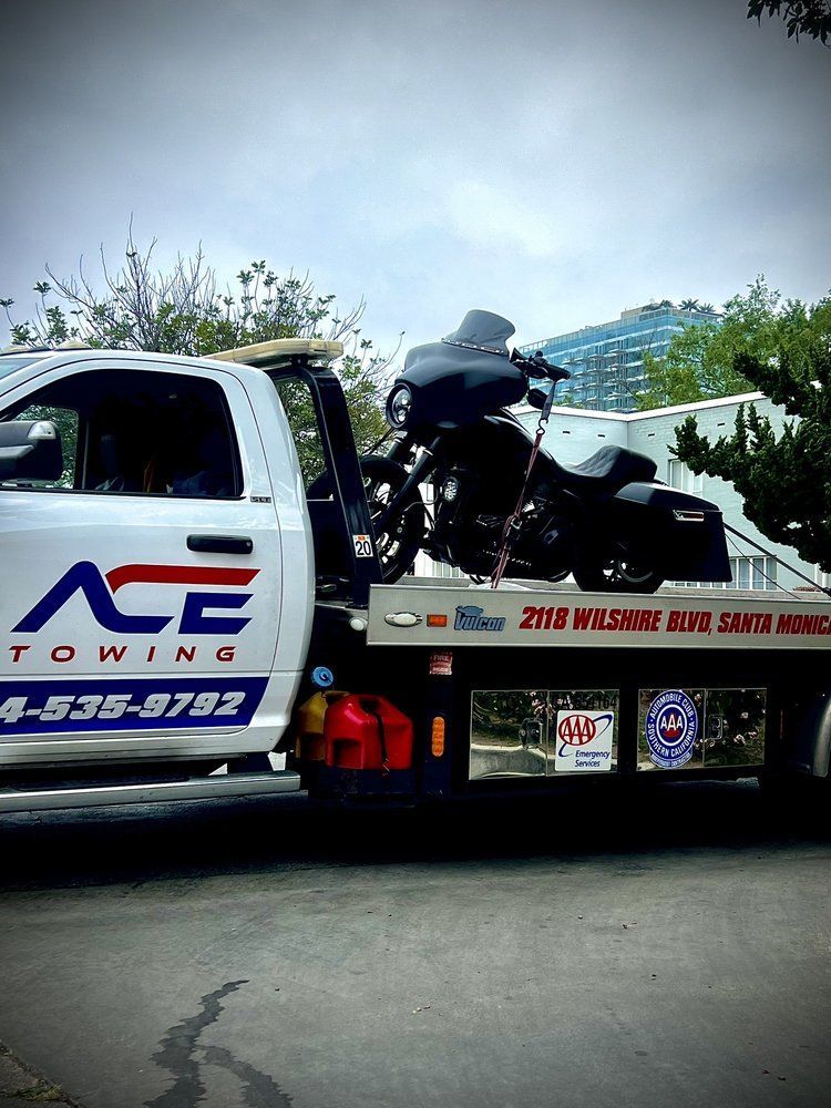 White tow truck with black motorcycle on flatbed. 