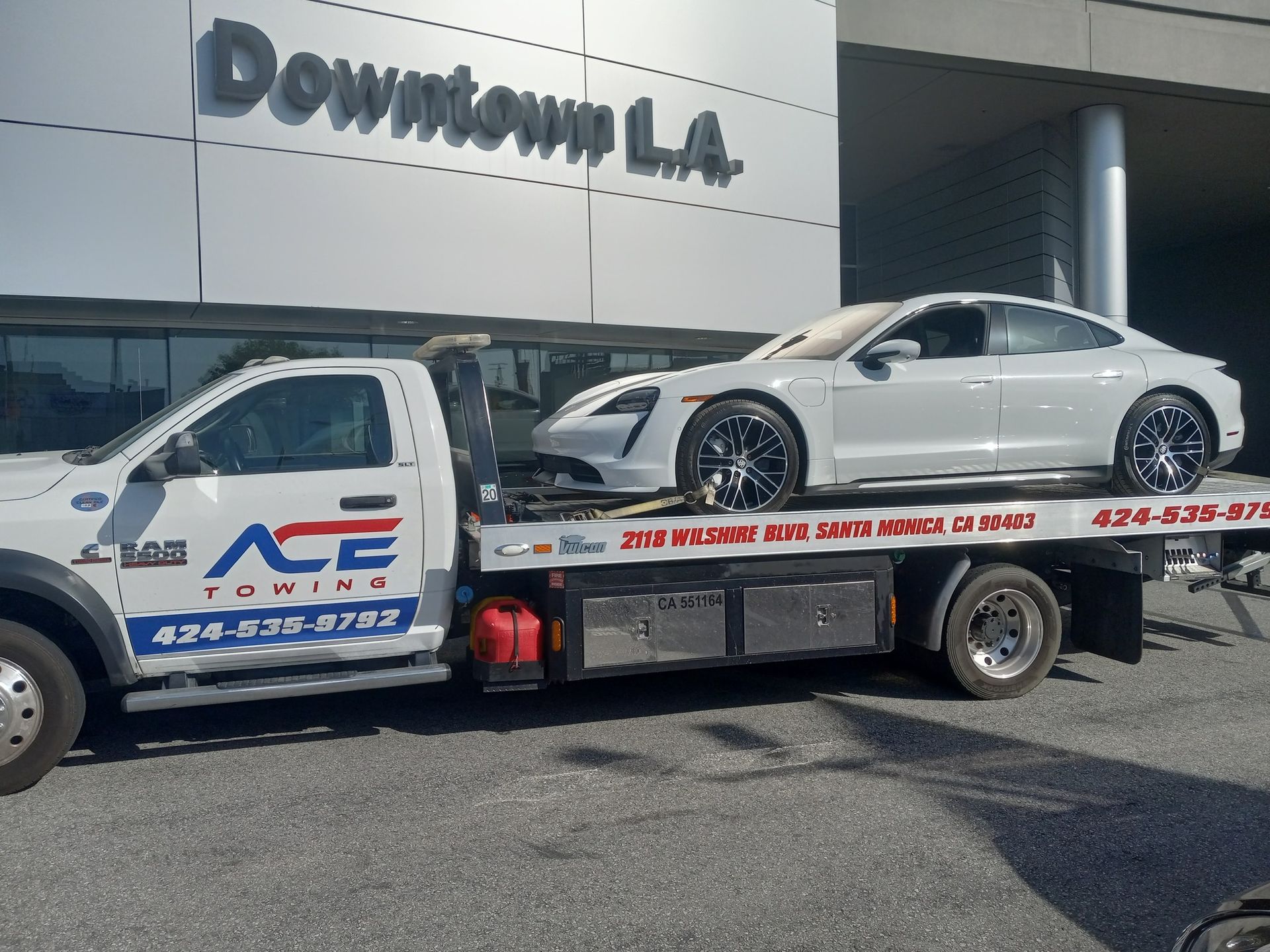 White car on ACE Towing flatbed truck in downtown LA.