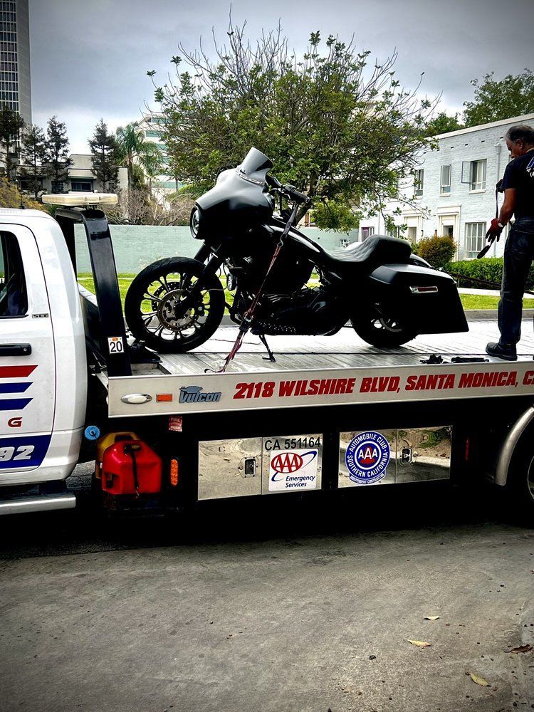 Black motorcycle on a tow truck, parked near a building in Santa Monica, California.