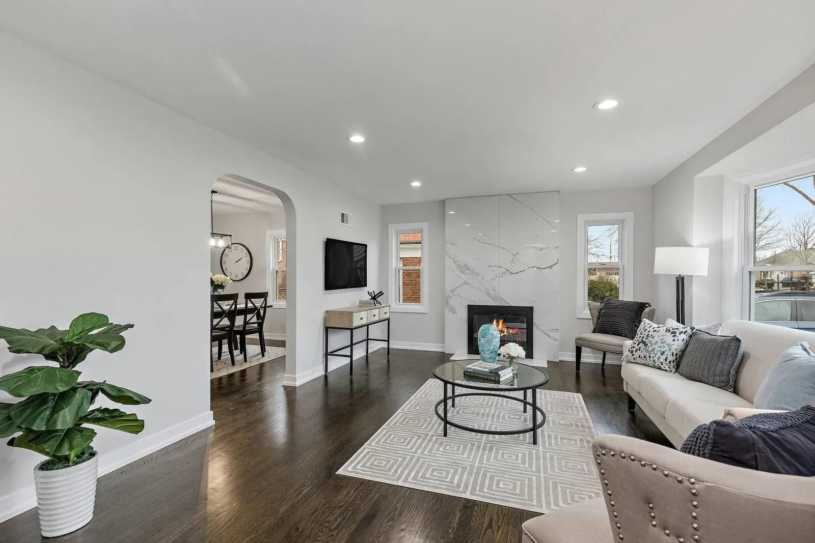 Living room with fireplace, white walls, dark wood floor, and light-colored furniture.