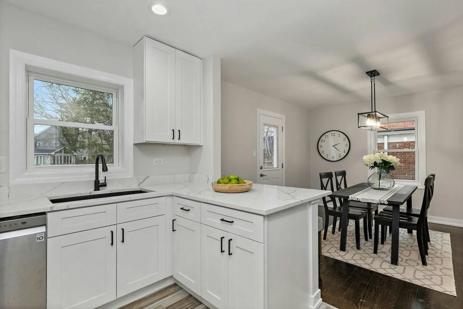 Modern white kitchen with countertop, cabinets, and a dining area with a table and chairs.