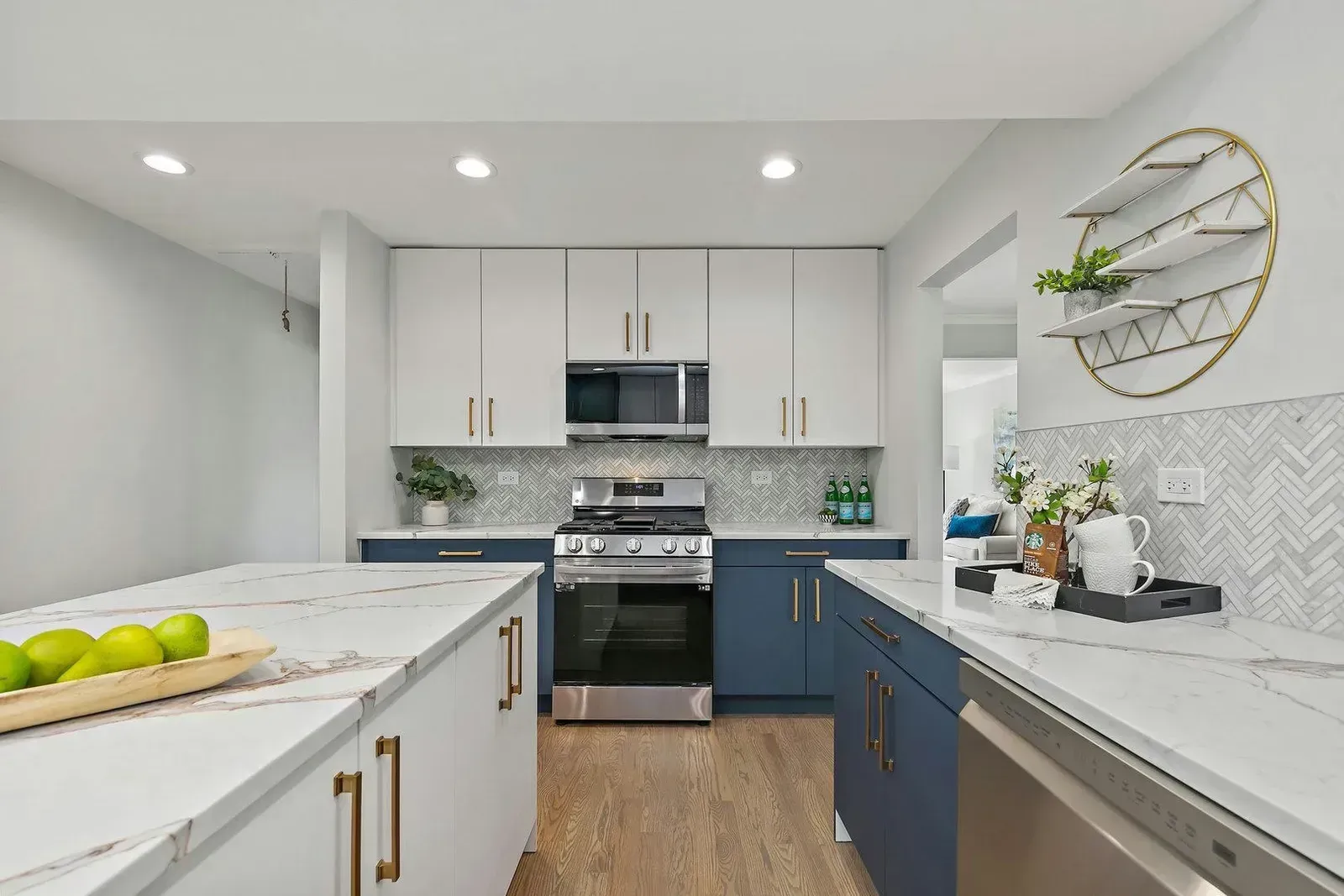Modern kitchen with white and blue cabinets, stainless steel appliances, and marble countertops.