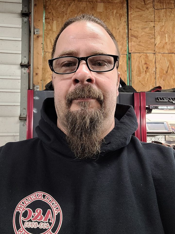 A man with a beard and glasses is wearing a black hoodie.