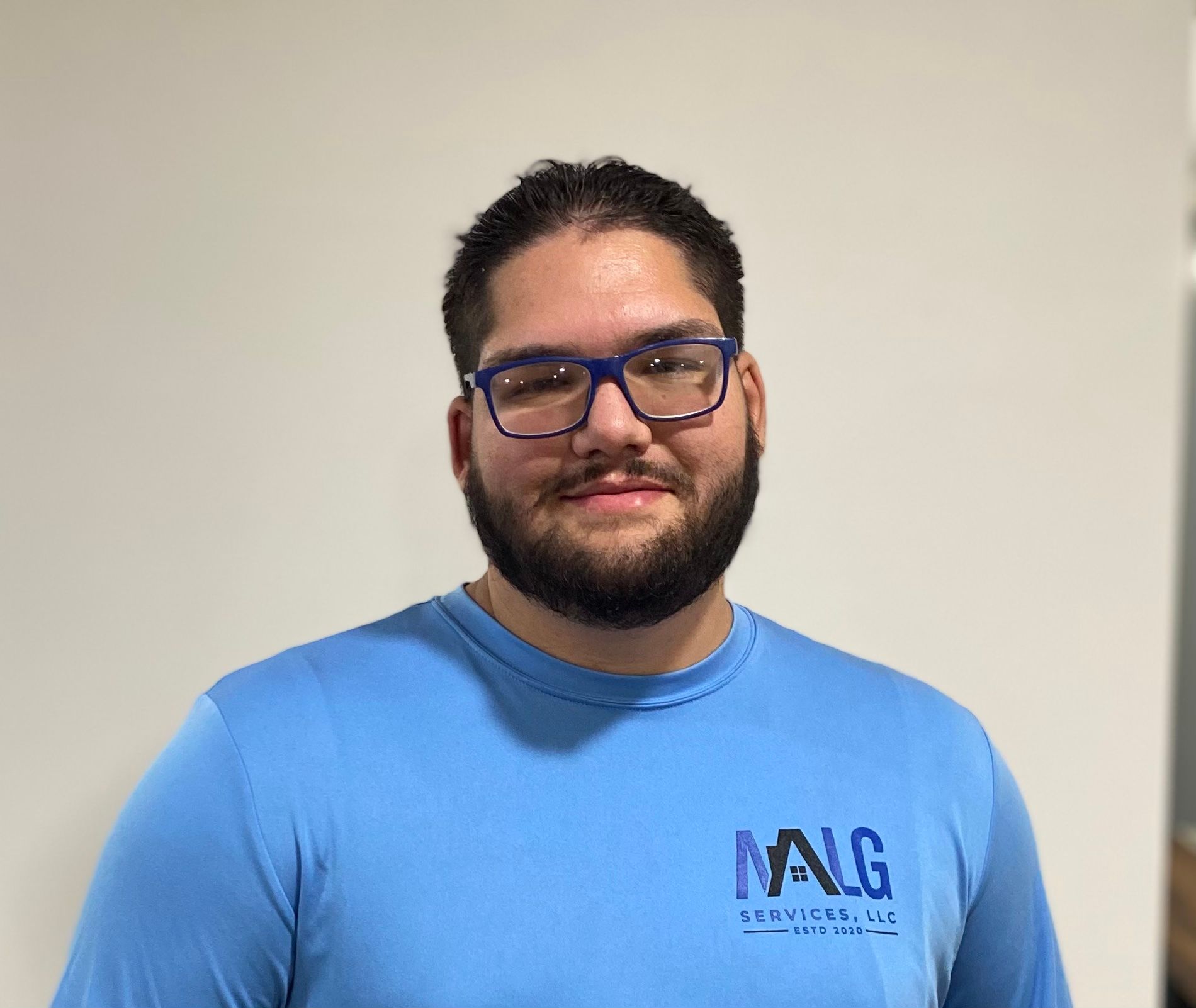 A man with a beard and glasses is wearing a blue shirt.