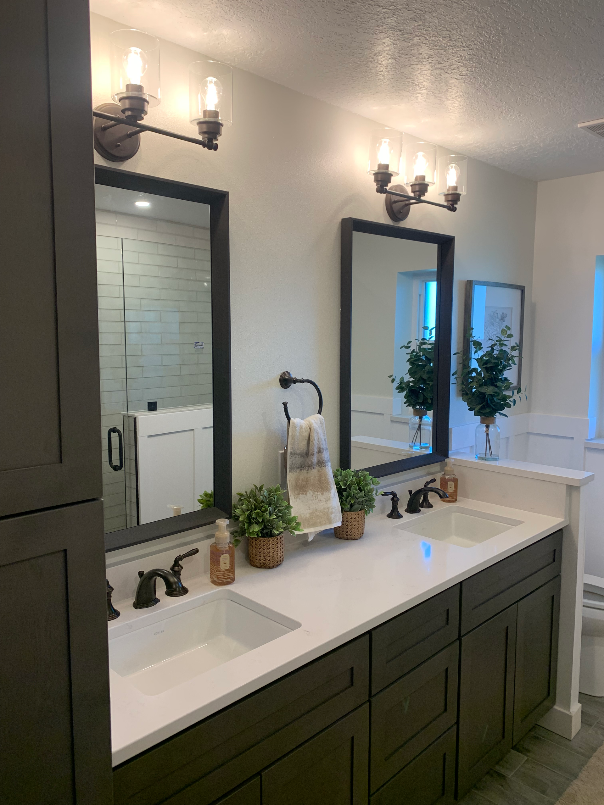 A shower with white tiles and a black shower head.