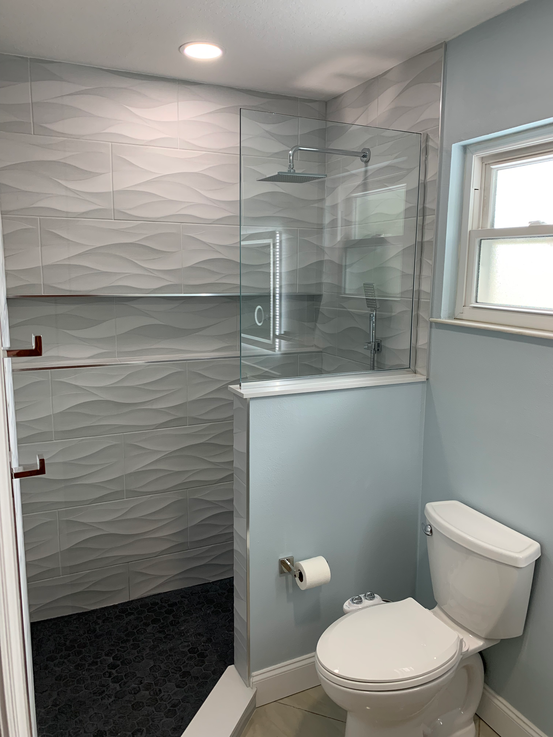 A walk in shower with a black and white tile floor.