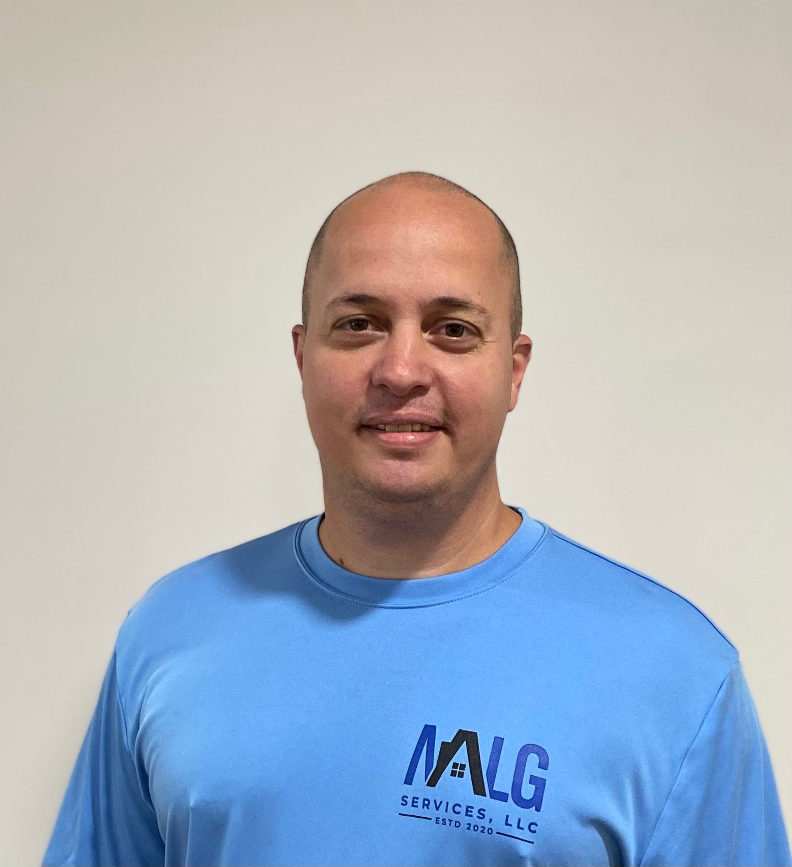 A bald man wearing a blue t-shirt with the word nalg on it.