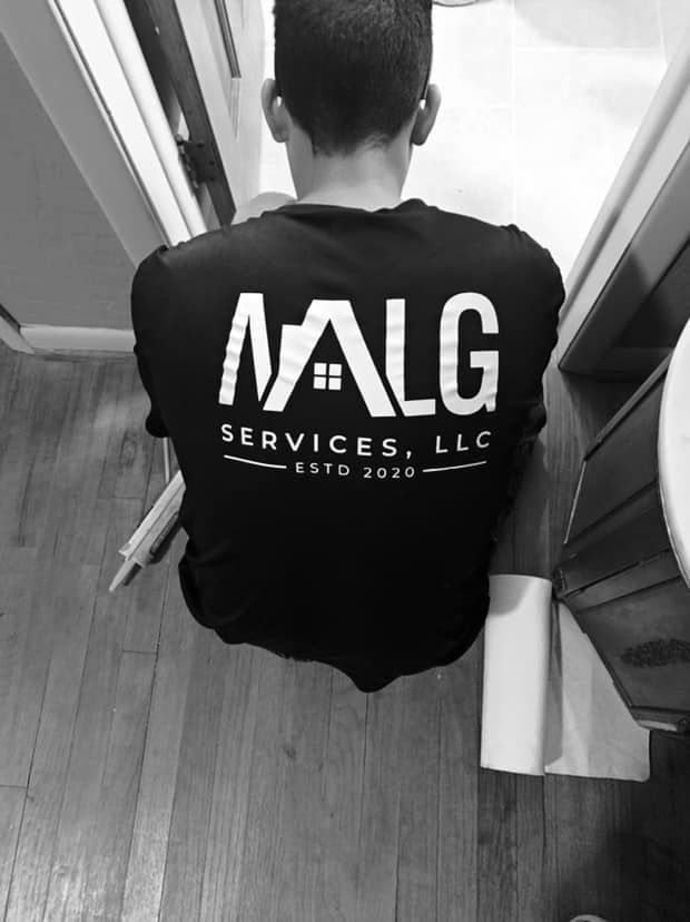 A man wearing a black shirt that says malg services llc