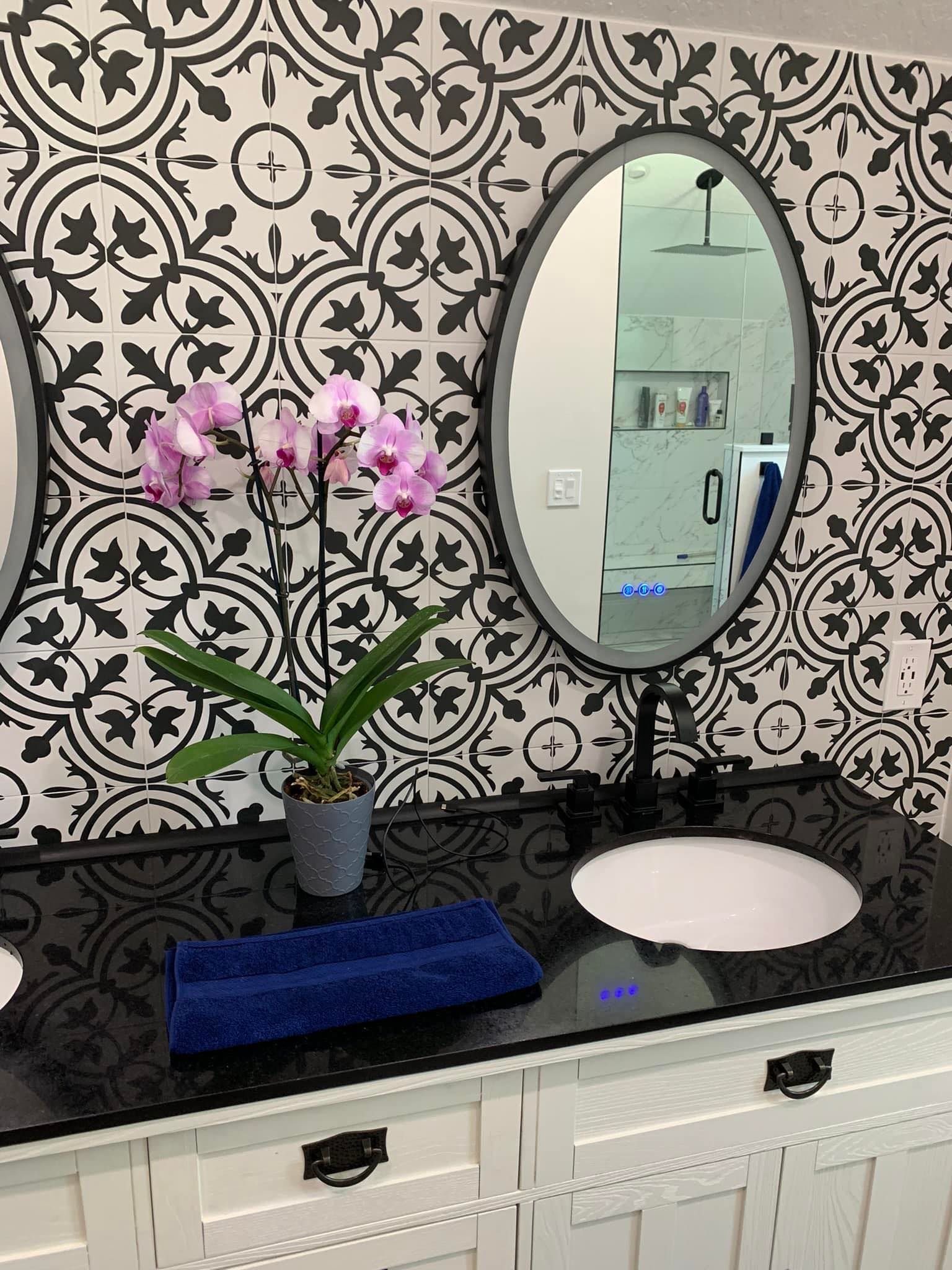 A bathroom with two sinks , two mirrors , and a potted plant.