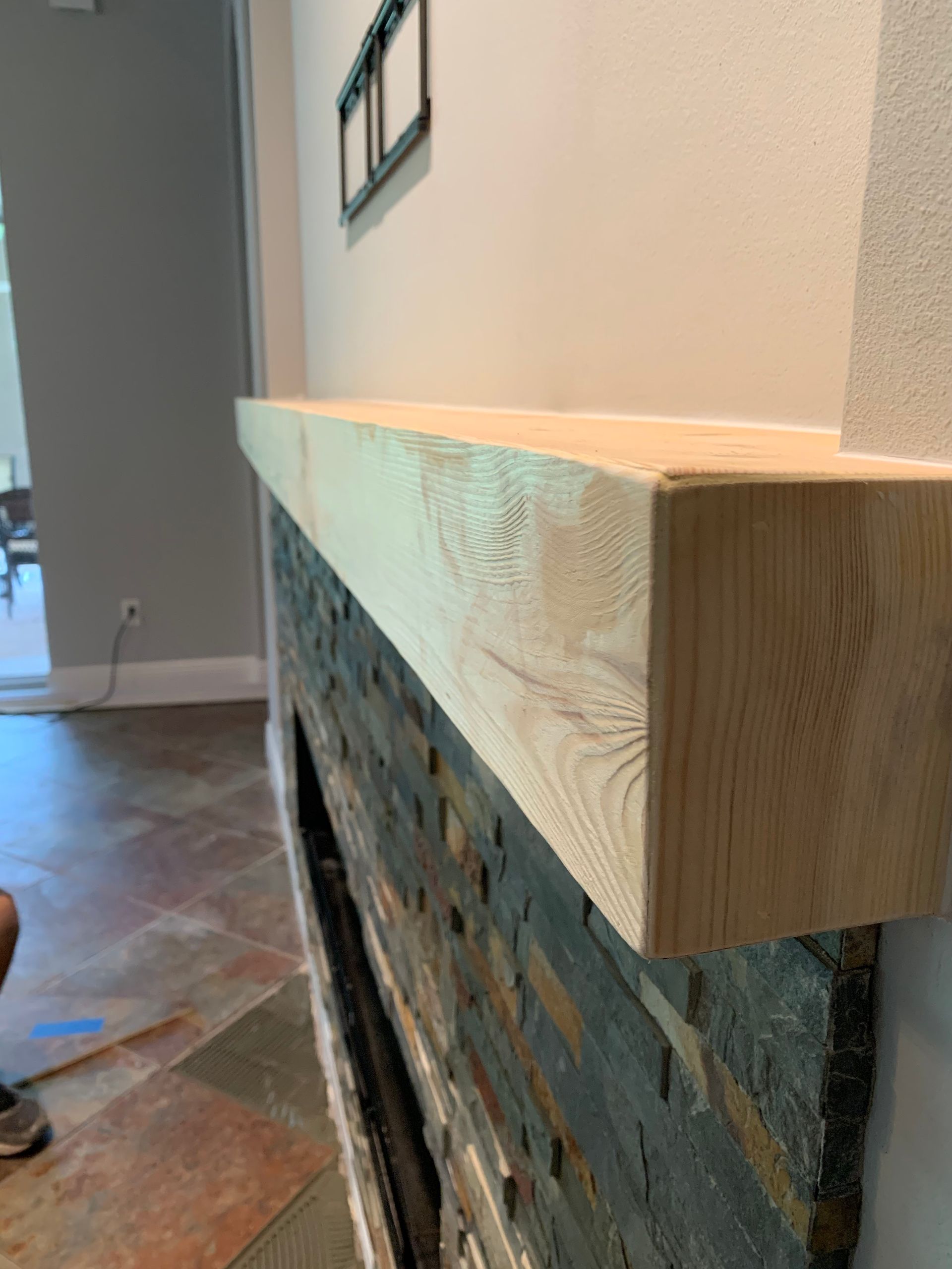 A wooden mantle is sitting on top of a stone fireplace.