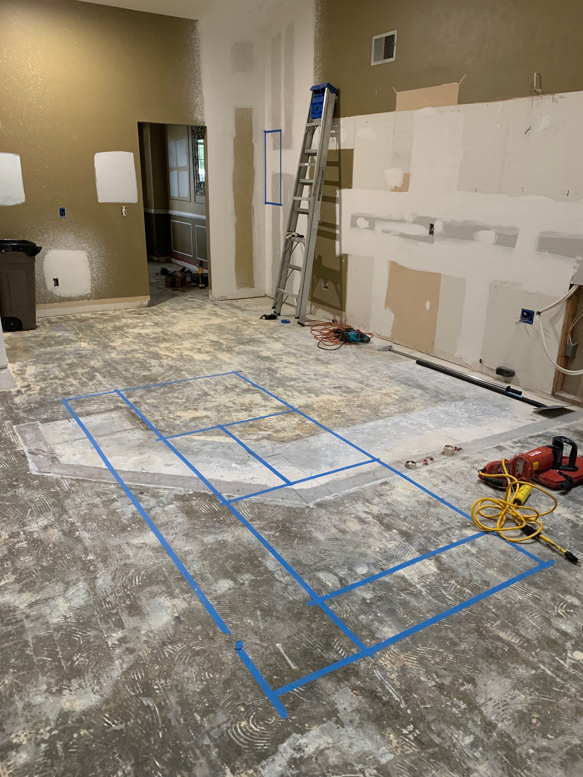 A room with a ladder and a tape measure on the floor.