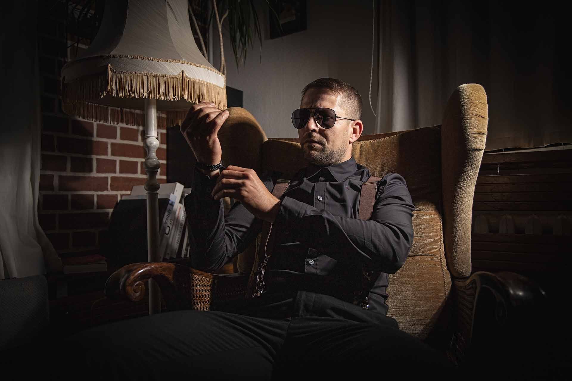 Ein Mann sitzt auf einem Stuhl und hält eine Lampe.
