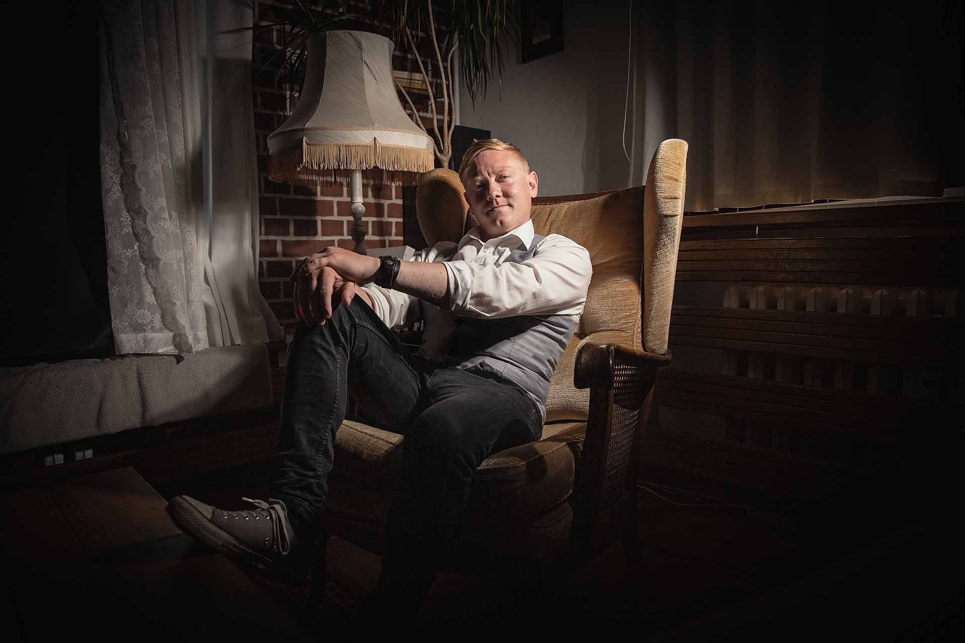 Ein Mann sitzt auf einem Stuhl vor einem Kamin.