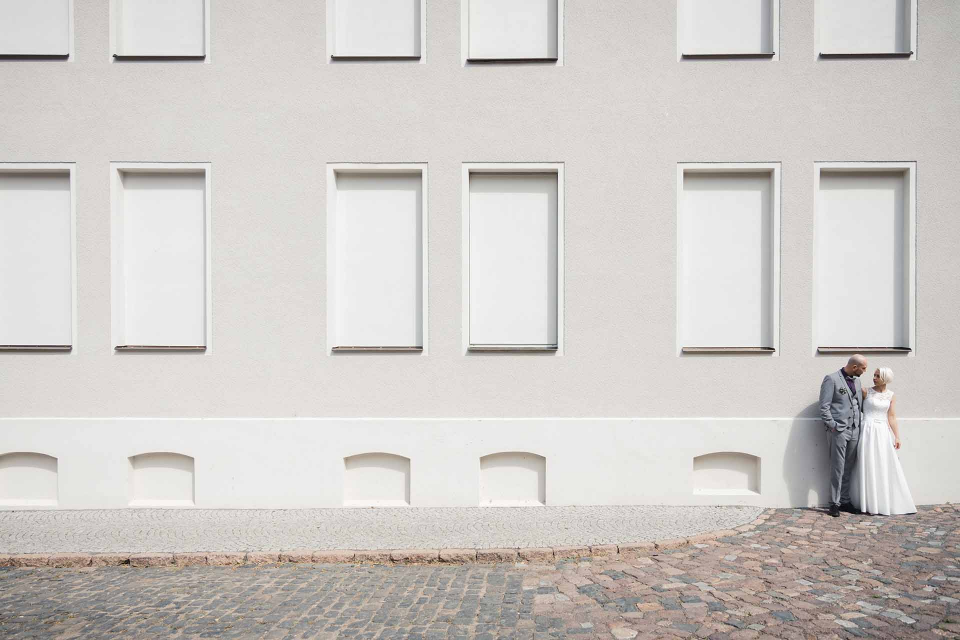 Eine Braut und ein Bräutigam stehen vor einem weißen Gebäude.