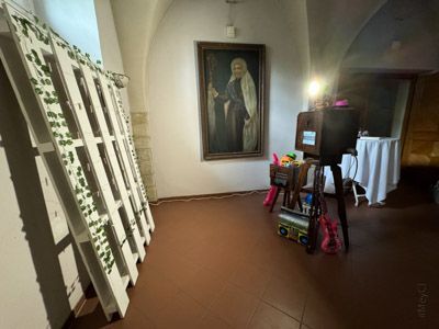 Eine Fotokabine in einem Raum mit einem großen Gemälde und weißen Paletten, die mit Grünzeug dekoriert sind.