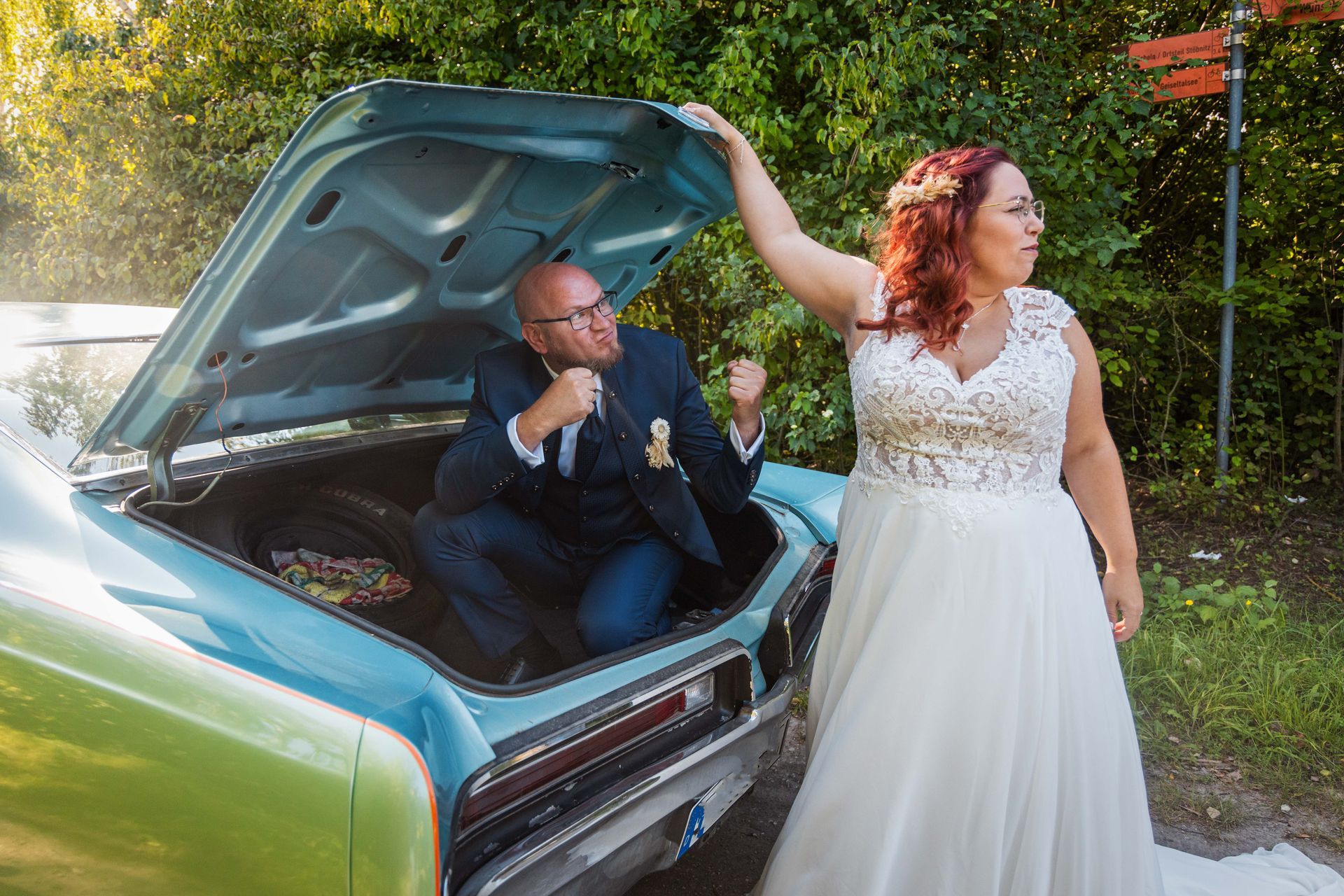 Eine Braut und ein Bräutigam posieren auf dem Rücksitz eines Autos für ein Foto.