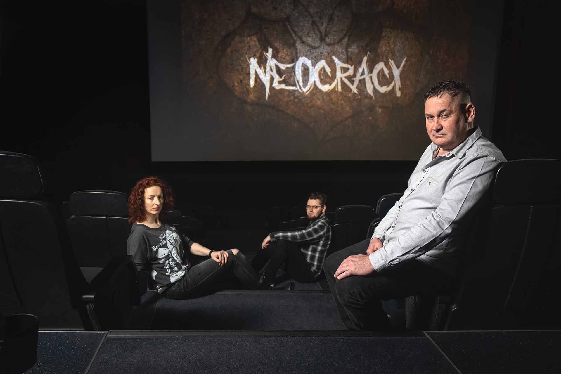 Eine Gruppe von Menschen sitzt vor einem Bildschirm , auf dem das Wort Demokratie steht.